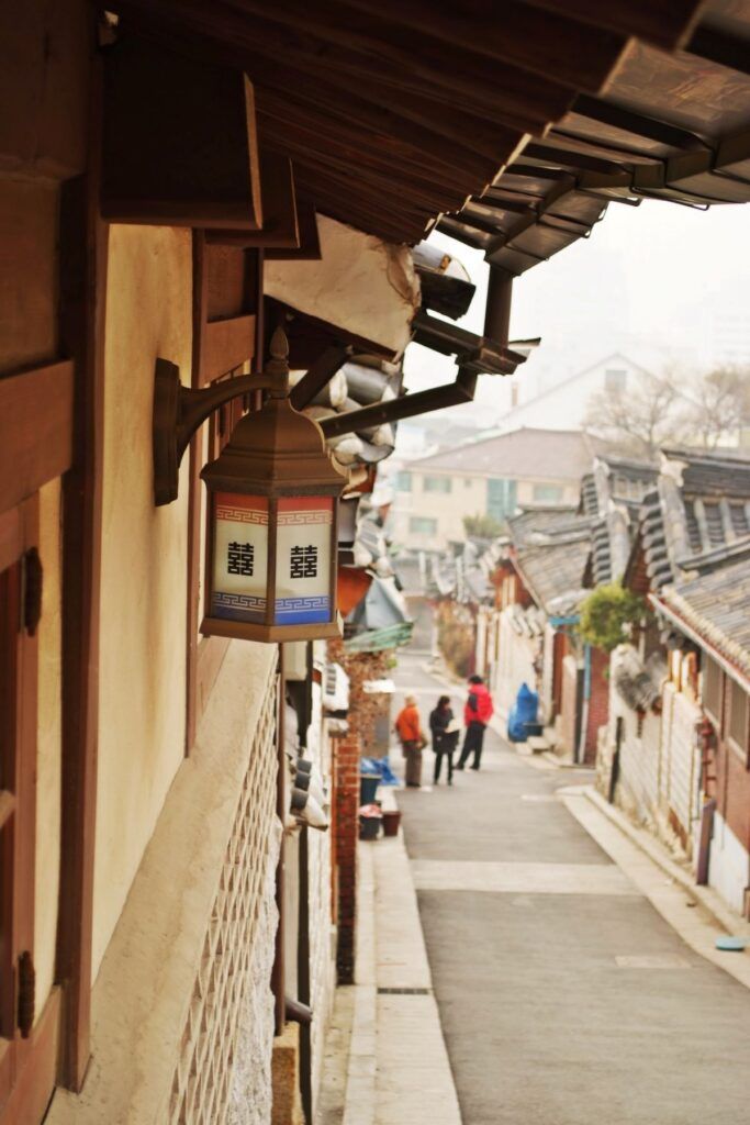 Trois personnes marchent entre des maisons à Bukchon Hanok en Corée du Sud.