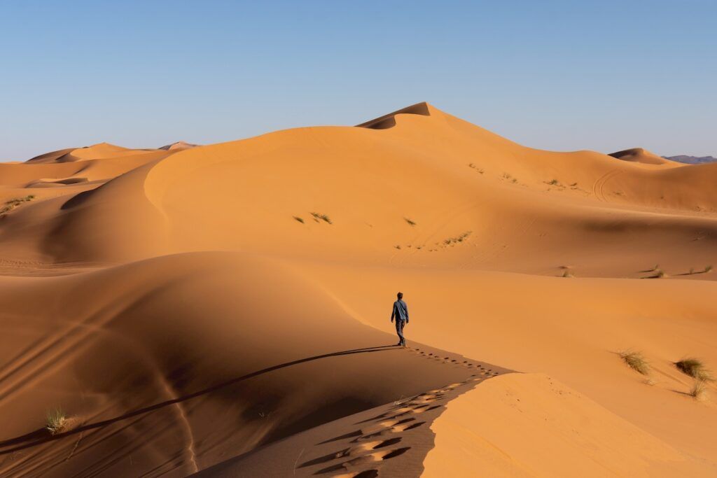 Un homme marche dans les dunes du désert