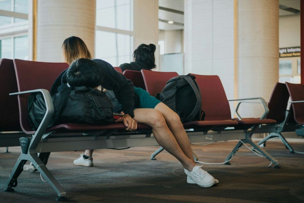Un garçon dort en s'appuyant sur son sac à dos à l'aéroport.