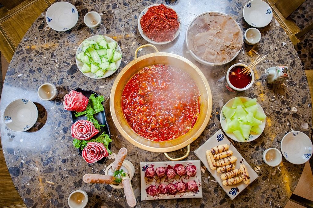 Table avec un hot pot vietnamien épicé entouré d'ingrédients frais