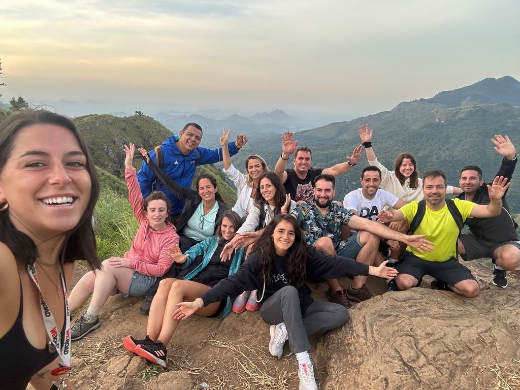 Un groupe de randonneurs souriants posant au sommet d’une montagne avec une vue panoramique sur les collines, lors d’un voyage organisé par WeRoad au Sri Lanka.