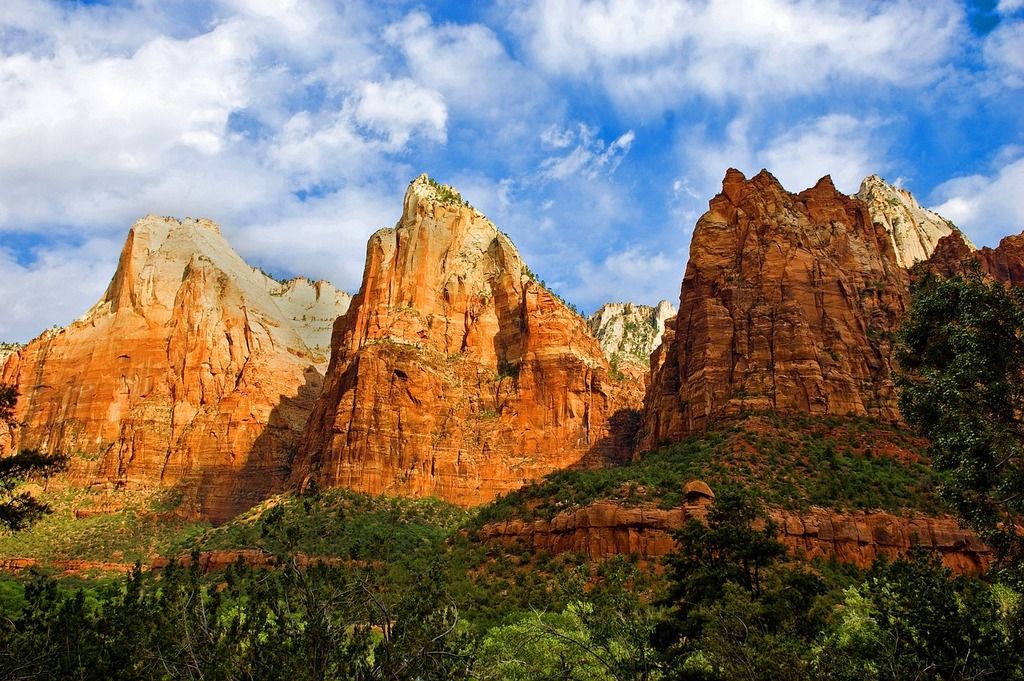 Paysage impressionnant du parc national de Zion, avec ses falaises rouges et son ciel bleu parsemé de nuages.