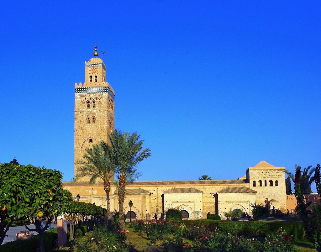 La mosquée Koutoubia à Marrakech, un symbole emblématique entouré de jardins luxuriants sous un ciel bleu.