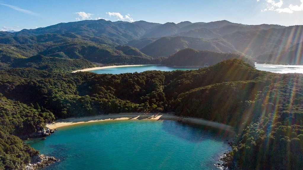 Vue aérienne du parc national d’Abel Tasman en Nouvelle-Zélande, avec des plages dorées et une mer turquoise.