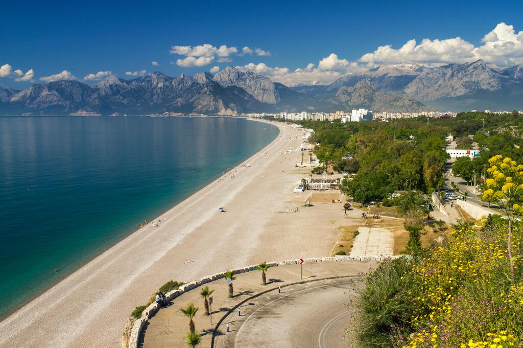 Plage de galets et vue sur les montagnes à Antalya, une destination balnéaire populaire en Turquie.