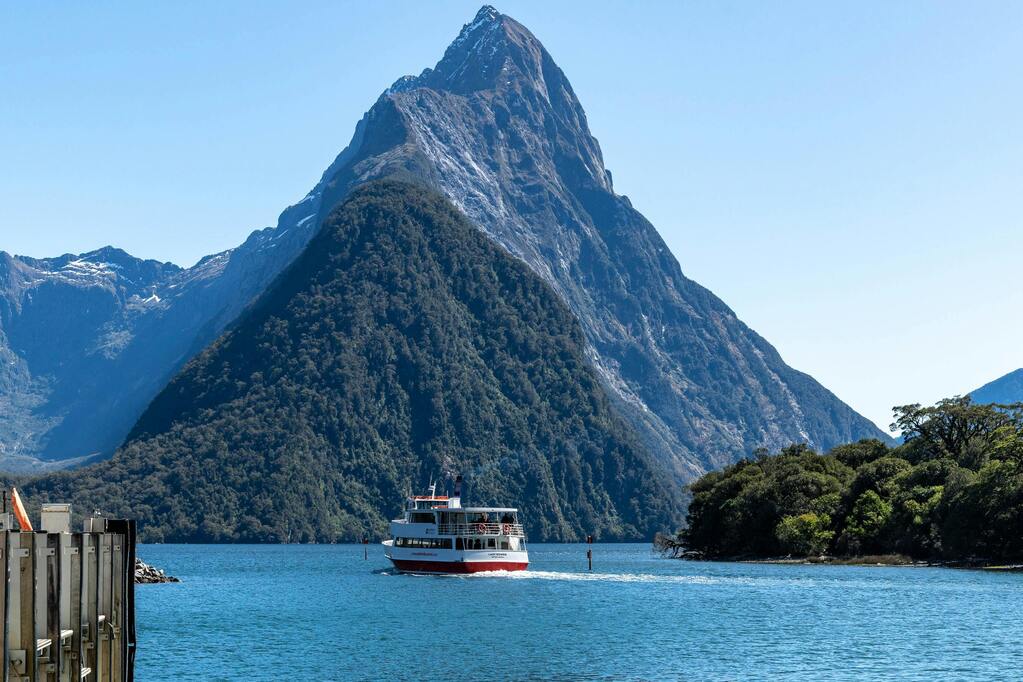 Un bateau de croisière naviguant dans le fjord de Milford Sound en Nouvelle-Zélande, entouré de montagnes imposantes.