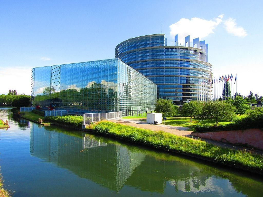 Le bâtiment moderne du Parlement européen à Strasbourg, avec sa façade en verre reflétant le canal adjacent.