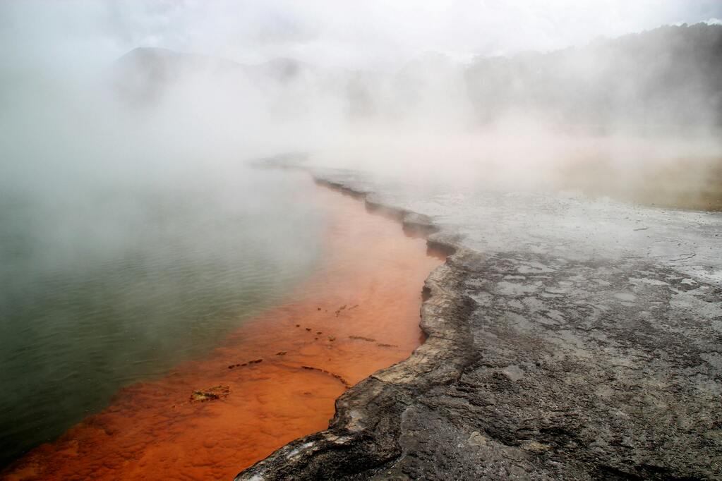 Les sources chaudes de Champagne Pool à Wai-O-Tapu, en Nouvelle-Zélande, avec des vapeurs géothermiques et des eaux colorées.