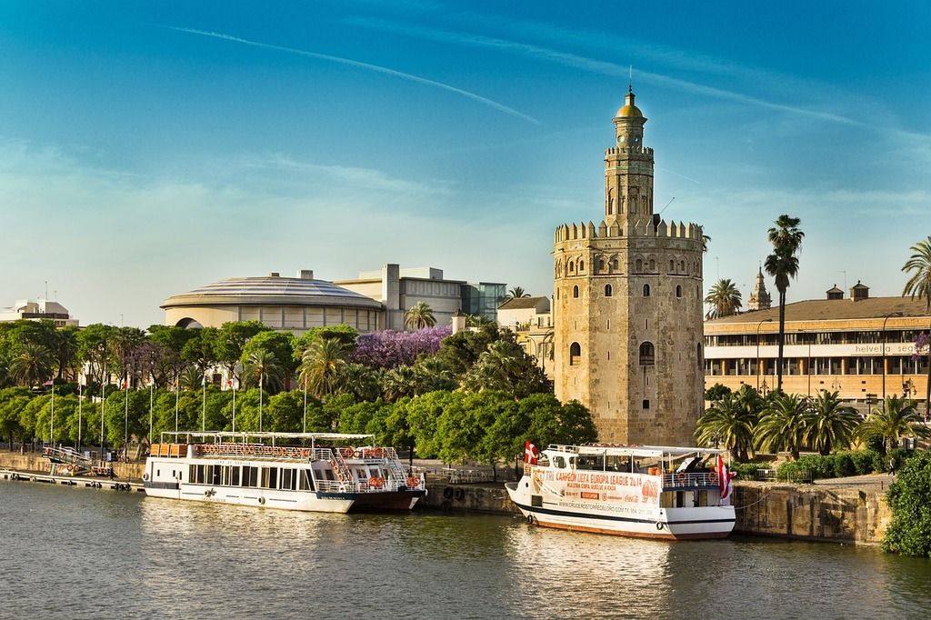 Torre del Oro à Séville: tour historique sur les rives du Guadalquivir avec des bateaux de croisière à quai.