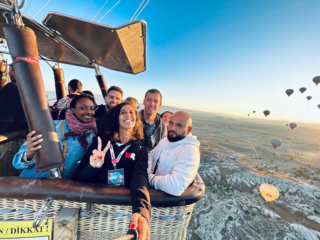 Groupe de voyageurs Weroad dans une montgolfière survolant la Cappadoce au lever du soleil.