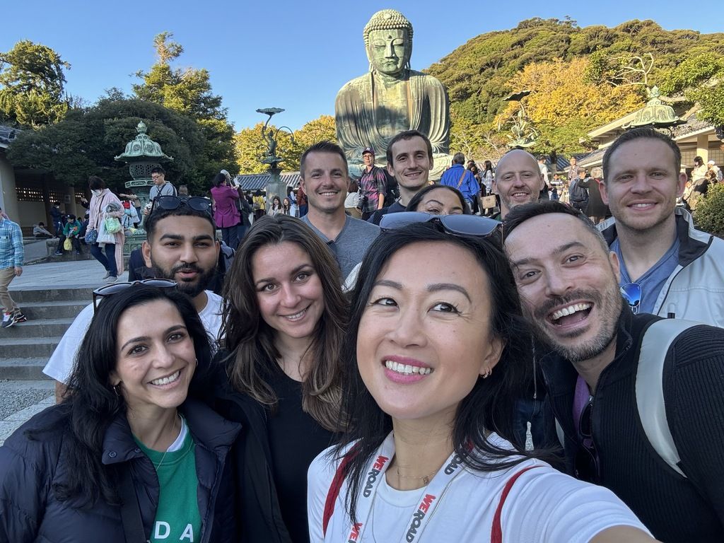 Groupe WeRoad posant devant la Grande Statue du Bouddha à Kamakura lors d'un voyage organisé au Japon.