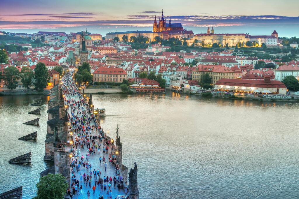 Vue panoramique sur le pont Charles et le château de Prague au coucher du soleil.