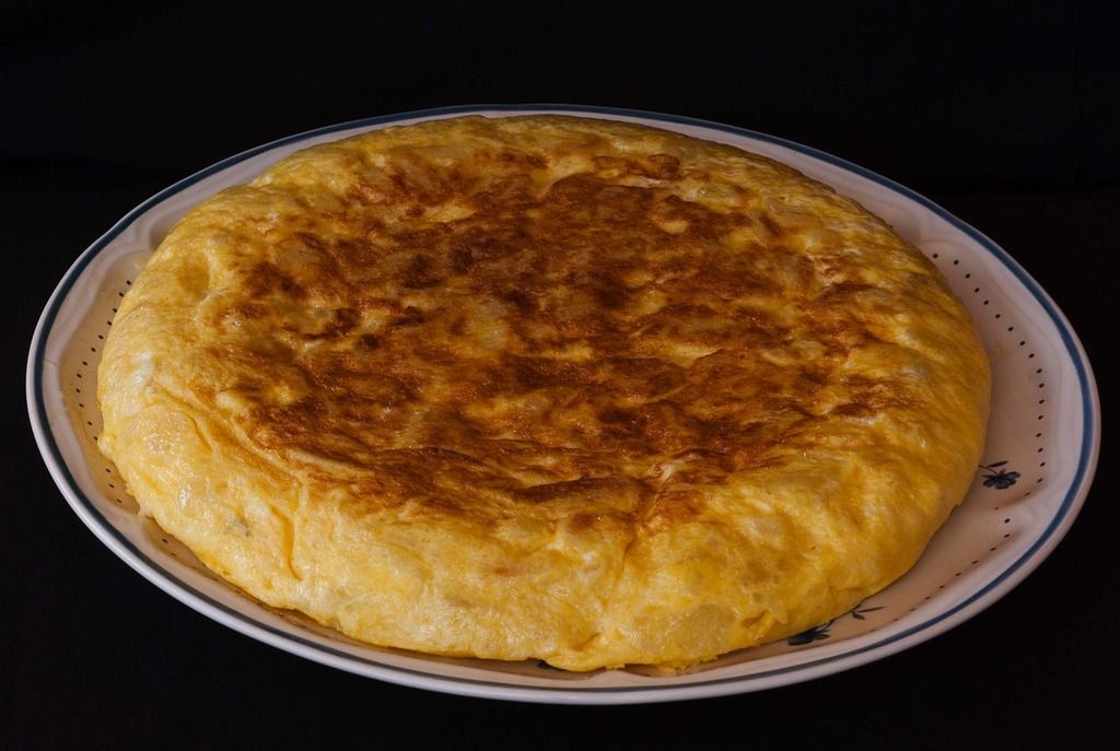 Tortilla espagnole classique, dorée et servie sur une assiette blanche.