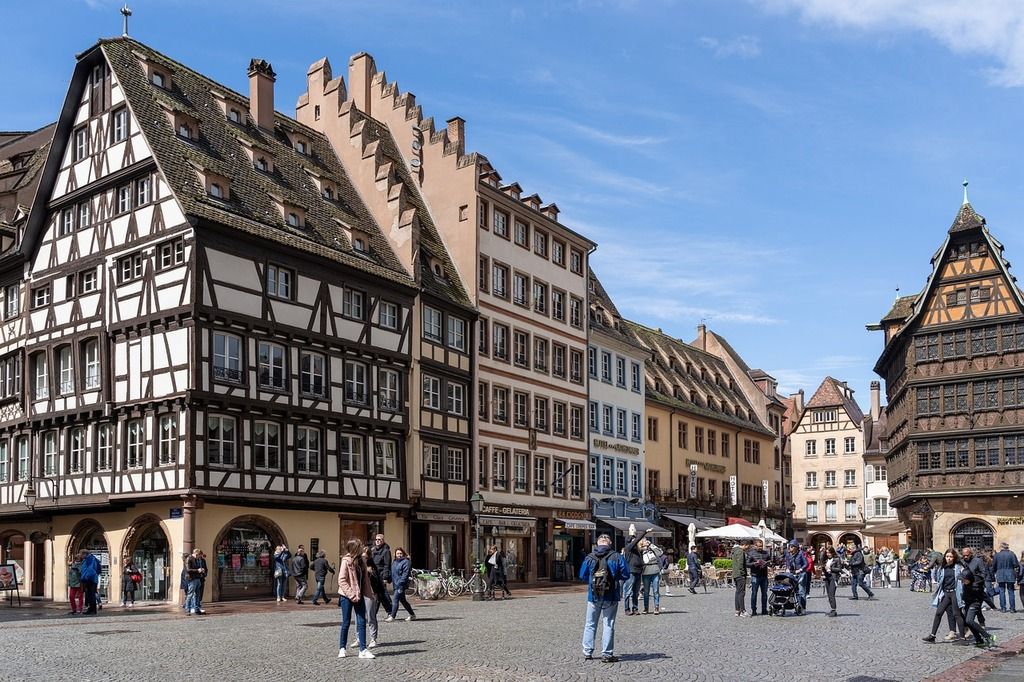 Place animée à Strasbourg, avec ses maisons à colombages traditionnelles et des visiteurs explorant la ville.