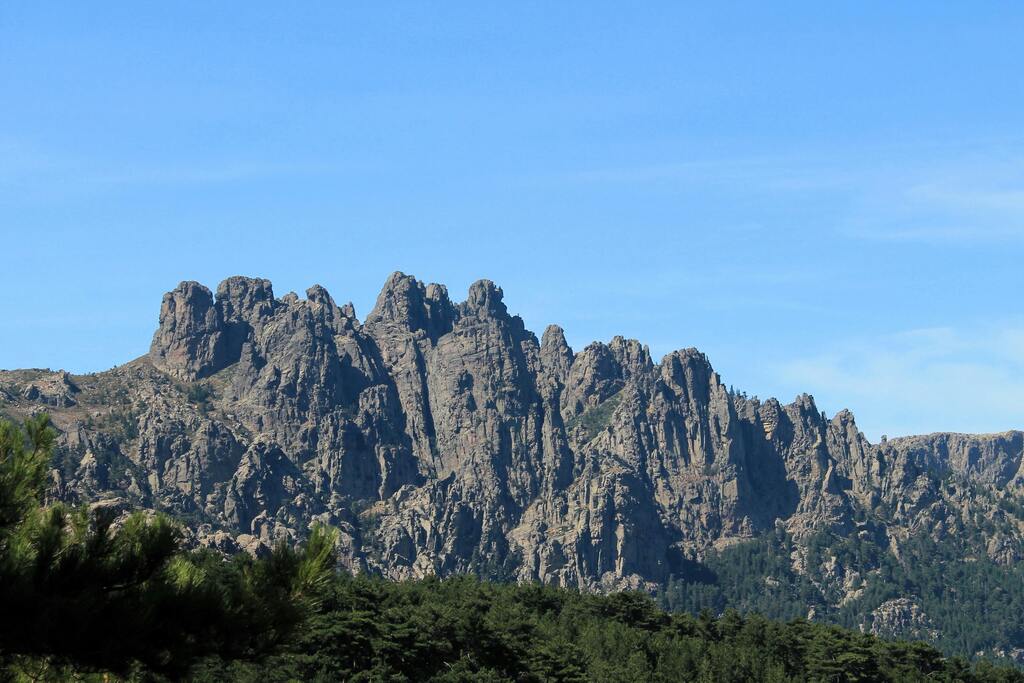 Les Aiguilles de Bavella, des formations rocheuses impressionnantes au cœur de la Corse, avec une forêt en premier plan.