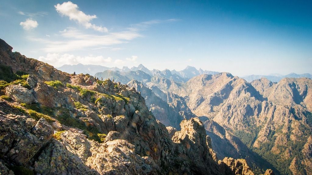 Paysage montagneux accidenté sous un ciel bleu clair en Corse, idéal pour la randonnée et l'exploration.