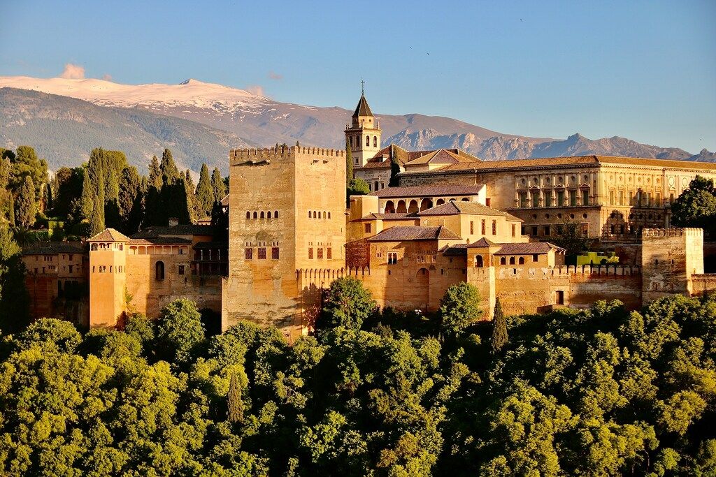 L’Alhambra de Grenade entourée de forêts et montagnes au coucher du soleil