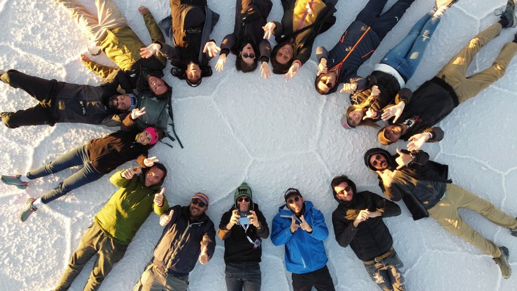 Groupe de voyageurs WeRoad allongés en cercle sur le salar d'Uyuni en Bolivie