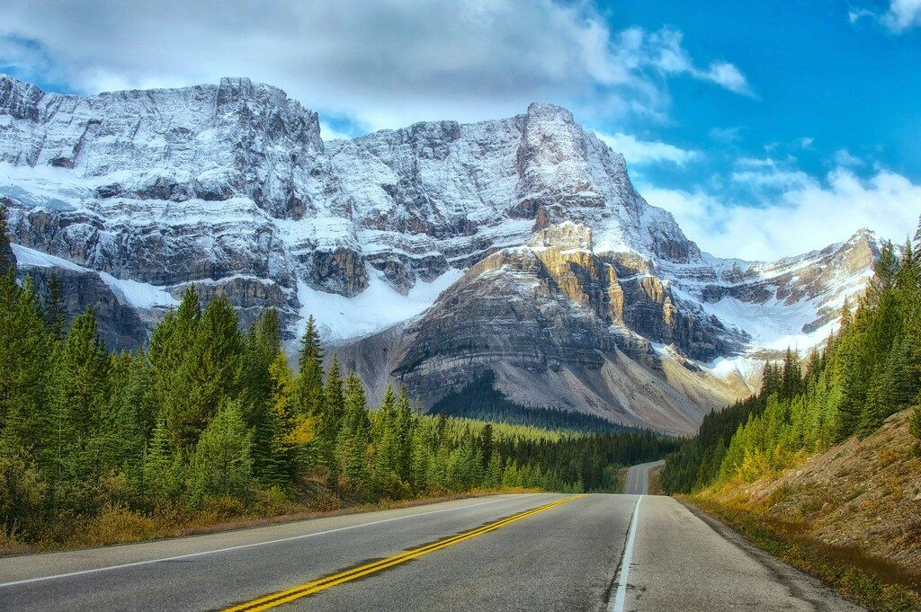 Route au milieu des montagnes Rocheuses canadiennes sous la neige