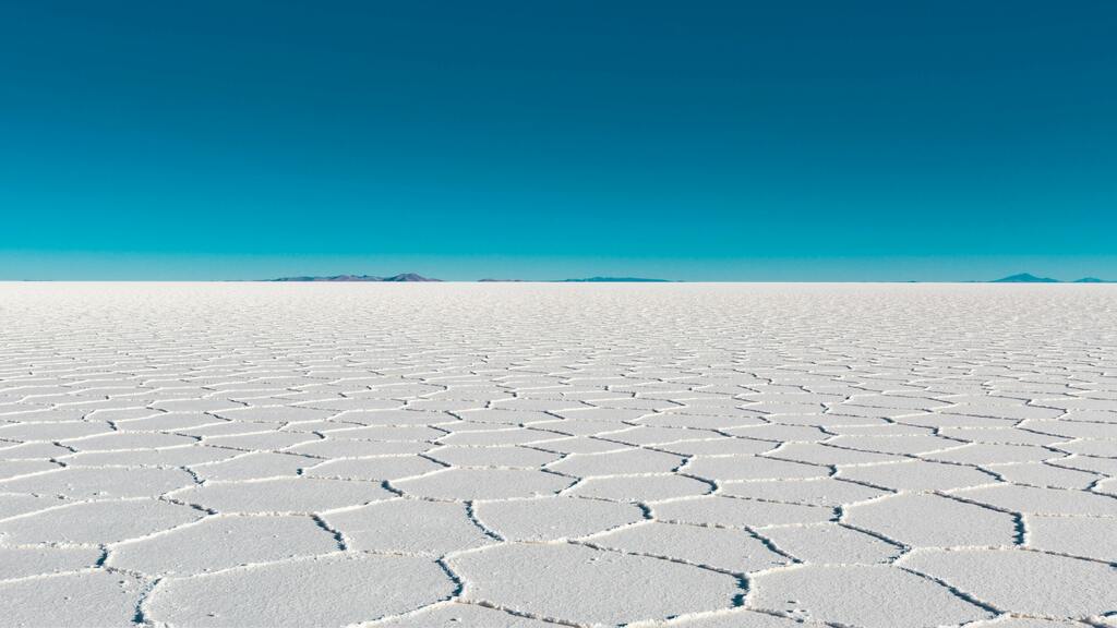 Vue panoramique du Salar de Uyuni, le plus grand désert de sel au monde, sous un ciel bleu éclatant.