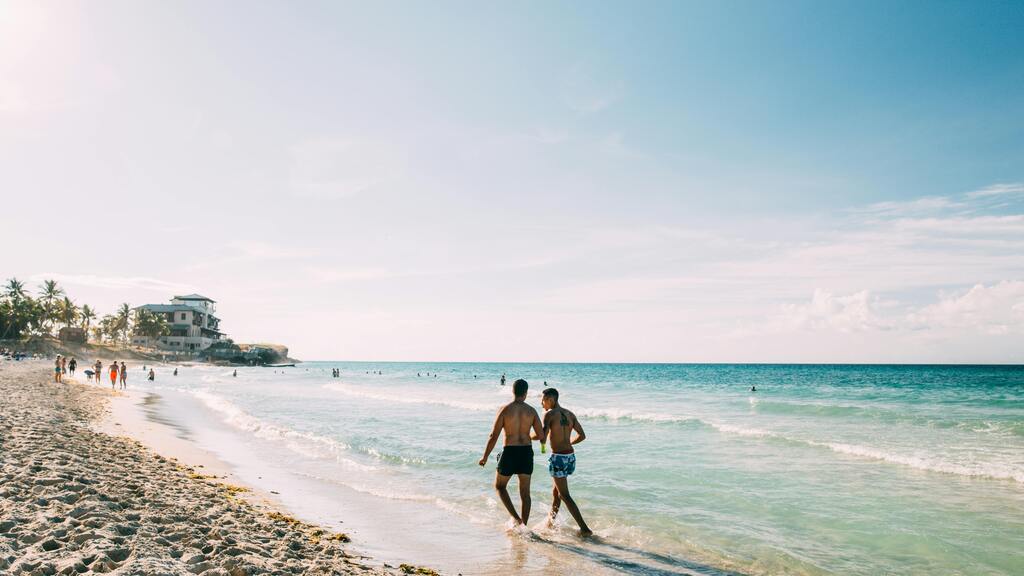 Deux hommes marchant dans l'eau sur une plage ensoleillée de Cuba.
