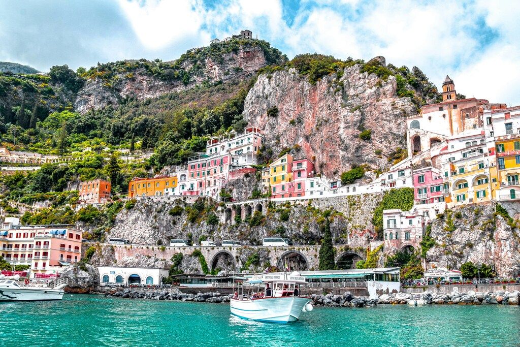 Maisons colorées perchées sur les falaises de la côte amalfitaine surplombant une mer turquoise.