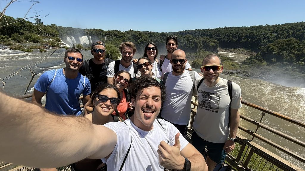 Groupe de voyageurs WeRoad souriants posant devant les impressionnantes chutes d’Iguazú lors d’un voyage organisé en Amérique du Sud
