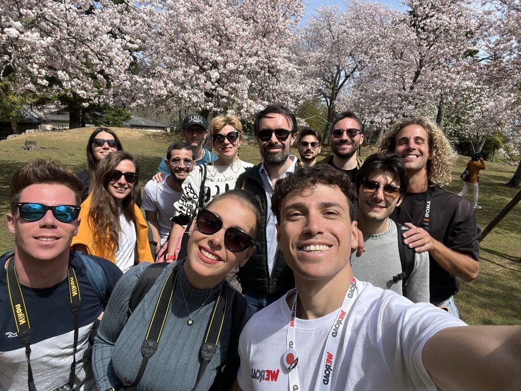 Groupe de voyageurs WeRoad souriants pendant la floraison des cerisiers au Japon.