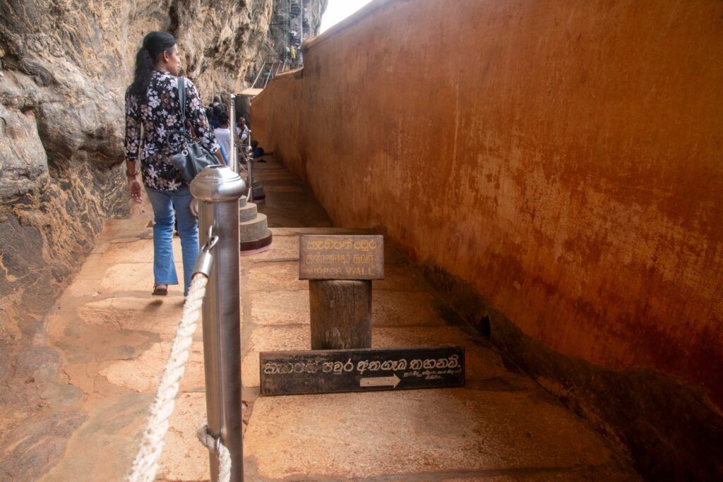 Femme marchant le long de la paroi rocheuse et du Miroir (Mirror Wall) de Sigiriya.