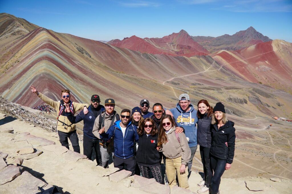 Groupe de voyageurs WeRoad posant devant les Montagnes Arc-en-ciel (Rainbow Mountains) au Pérou.