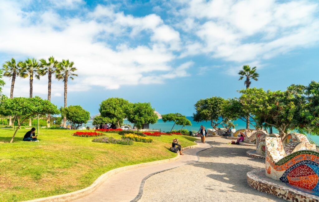 Un parc tropical luxuriant avec des palmiers et des pelouses verdoyantes, donnant sur un océan bleu.