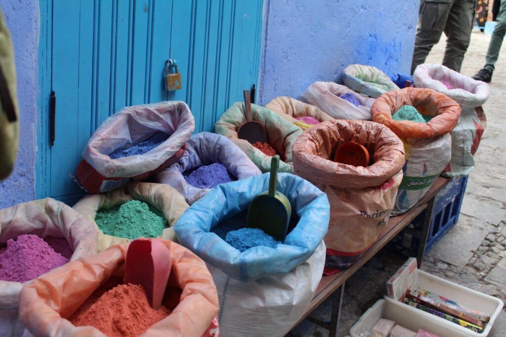 Sacs de pigments de couleurs vives (bleu, vert, ocre, violet) vendus dans les souks de Chefchaouen, Maroc.