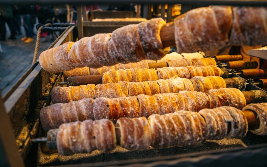 Trdelník (pâtisserie tchèque) enroulé sur des broches en train de griller au marché de Noël.