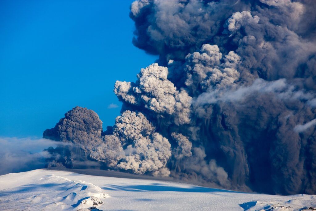 Éruption explosive du volcan Eyjafjallajökull en Islande, montrant un immense panache de cendres s'élevant au-dessus d'un glacier enneigé.