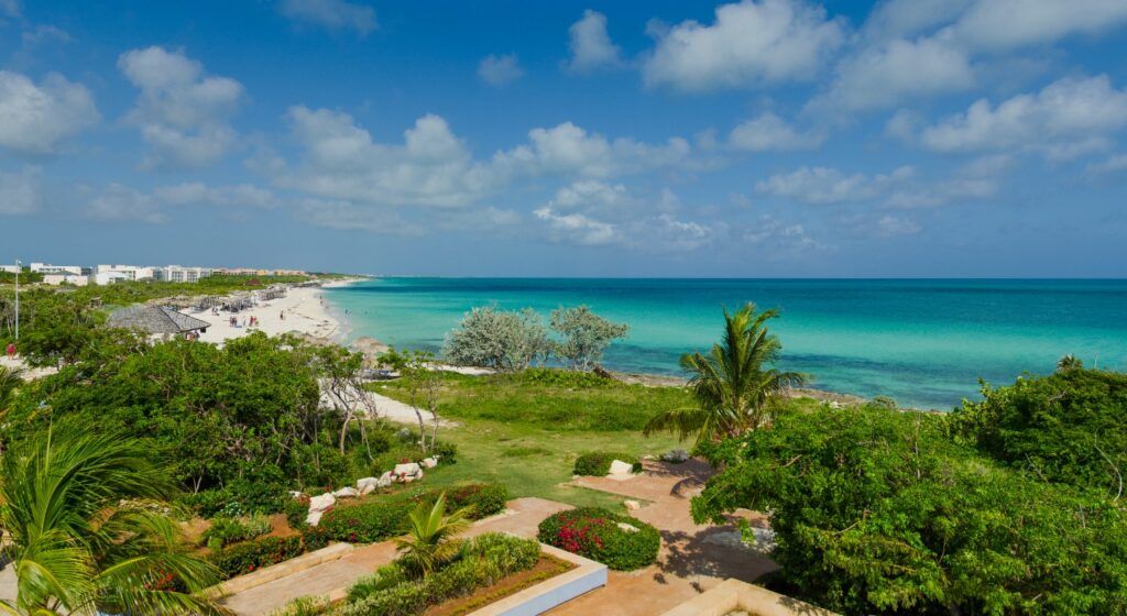 Vue panoramique de la plage de Cayo Santa María : mer turquoise, sable blanc et végétation luxuriante en bord de mer.