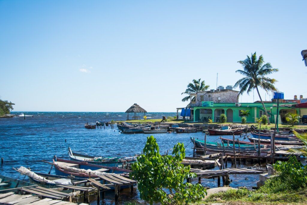 Vue d'un village de pêcheurs près de Playa Larga : cabanes, jetées en bois et petites embarcations sur l'eau, avec des palmiers et des bâtiments colorés.