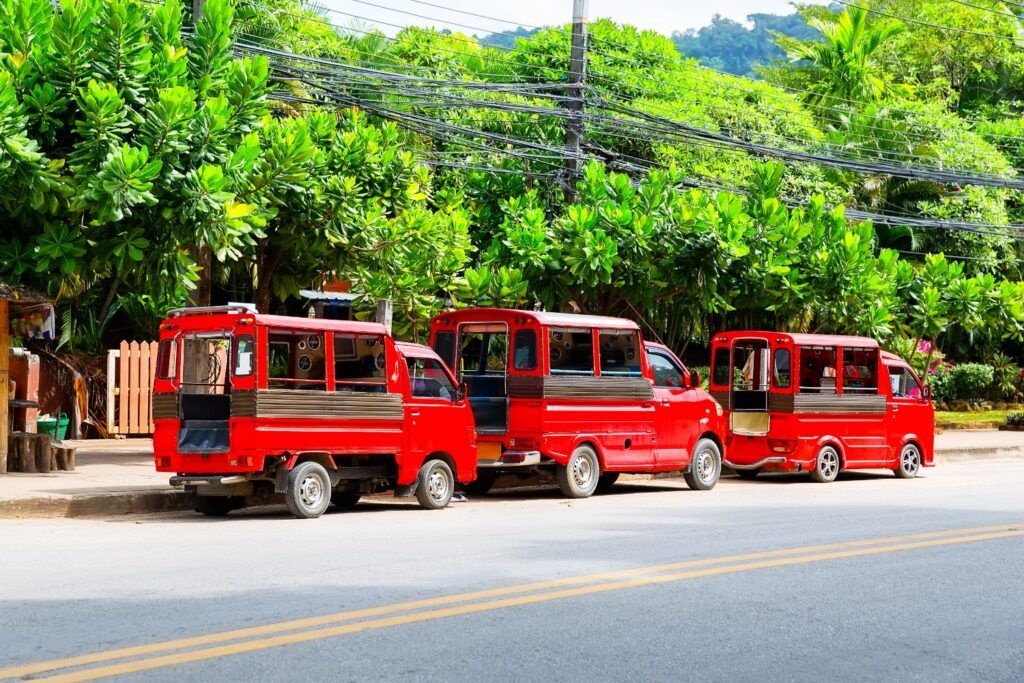 Trois Songthaews rouges alignés sur la route, le taxi collectif de Chiang Mai.
