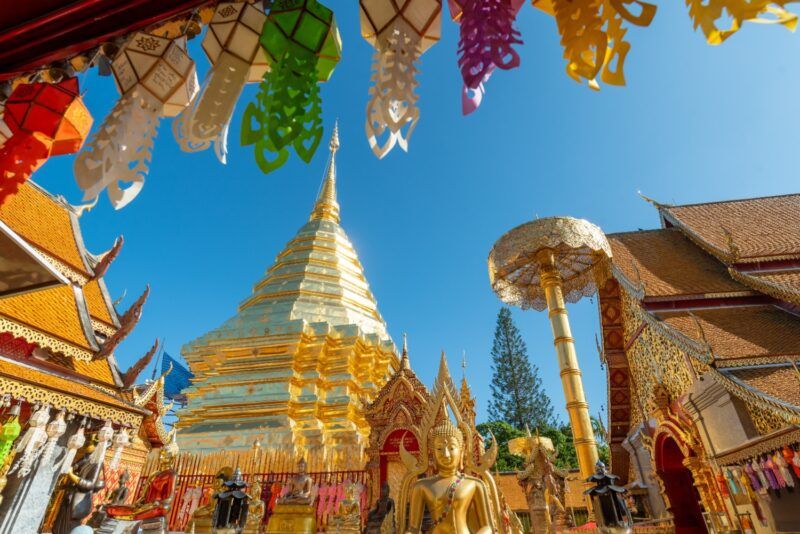 Pīer et lumineux du Wat Phra That Doi Suthep à Chiang Mai. Des lanternes Lanna colorées pendent au-dessus du Chedi principal doré sous un ciel bleu clair. Pīer et lumineux du Wat Phra That Doi Suthep à Chiang Mai. Des lanternes Lanna colorées pendent au-dessus du Chedi principal doré sous un ciel bleu clair.