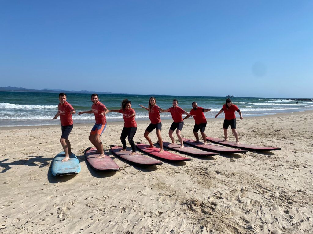 Un groupe de surfeurs pratiquant leur équilibre sur des planches de surf sur le sable d'une plage à Byron Bay, en Australie.