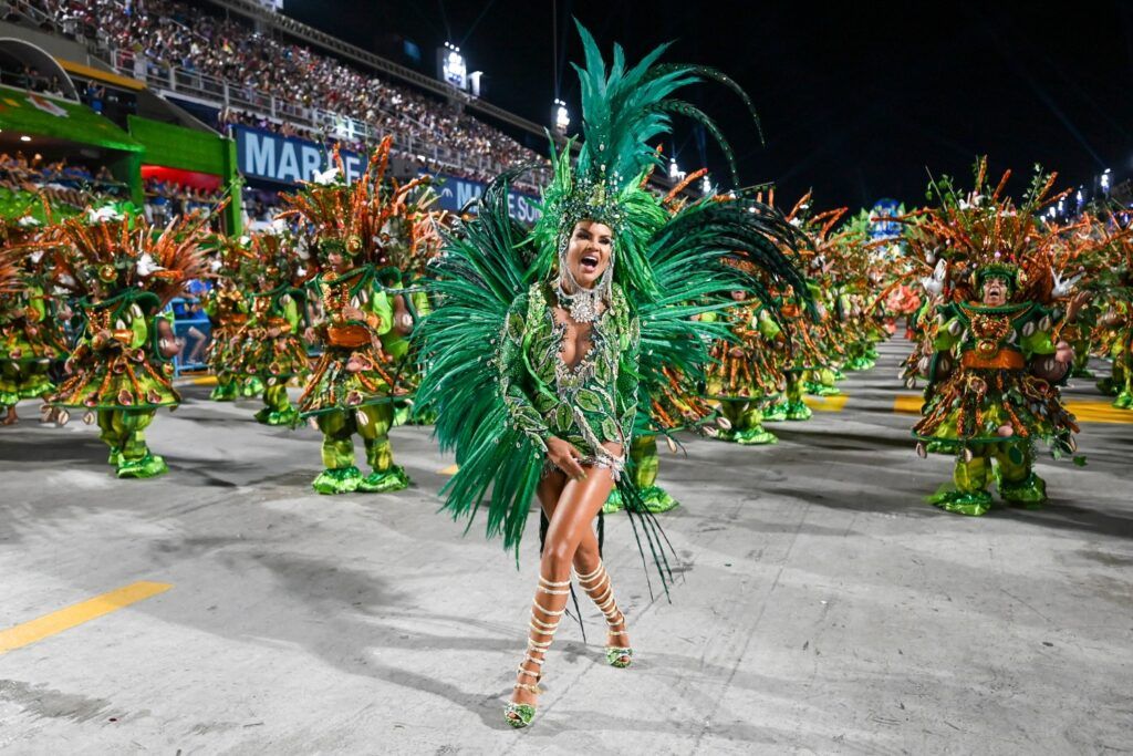 A samba dancer dressed in a bright green costume adorned with feathers parades during the carnival of Rio de Janeiro.