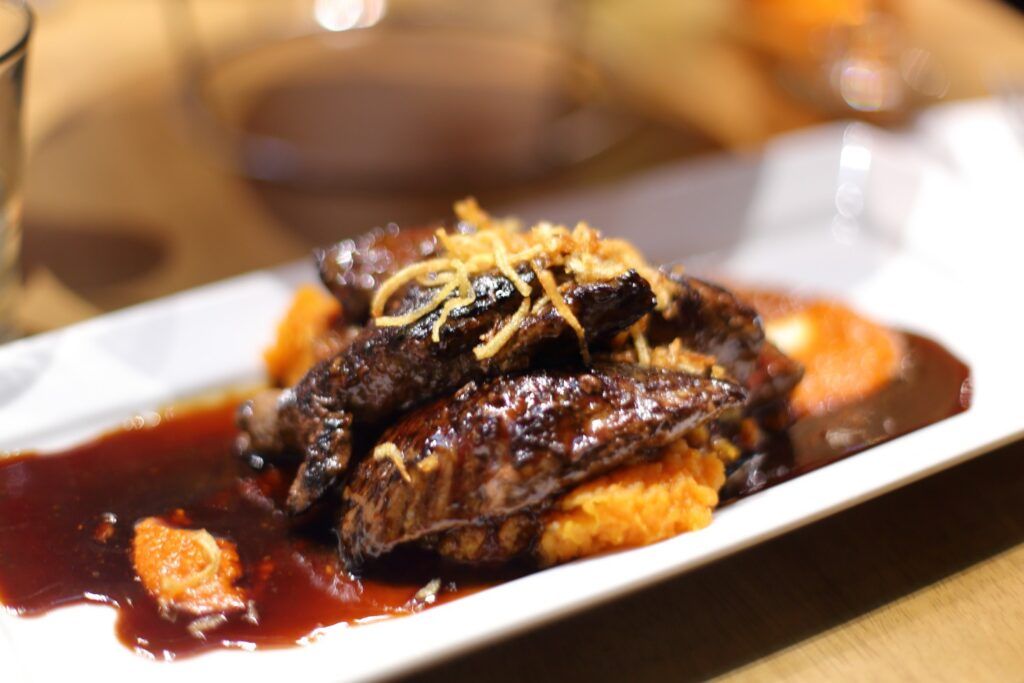 Un plat de viande de kangourou grillée servi avec une purée de patates douces et une réduction de sauce rouge.